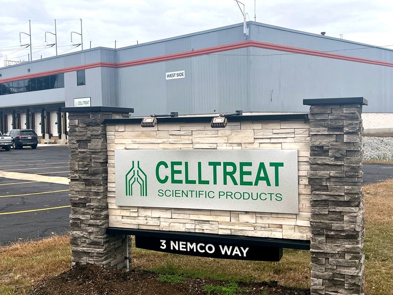 A sign for a lab supply company in front of an industrial building