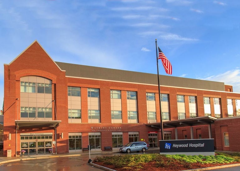 A brick three-story hospital building with traffic circle in front
