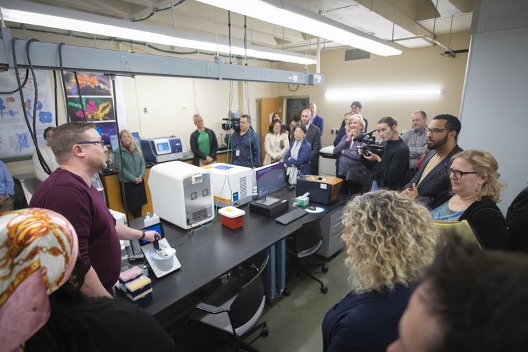A large group of people stand in a science lab