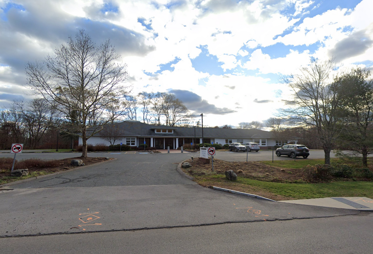 A one-story building behind a parking lot and driveway