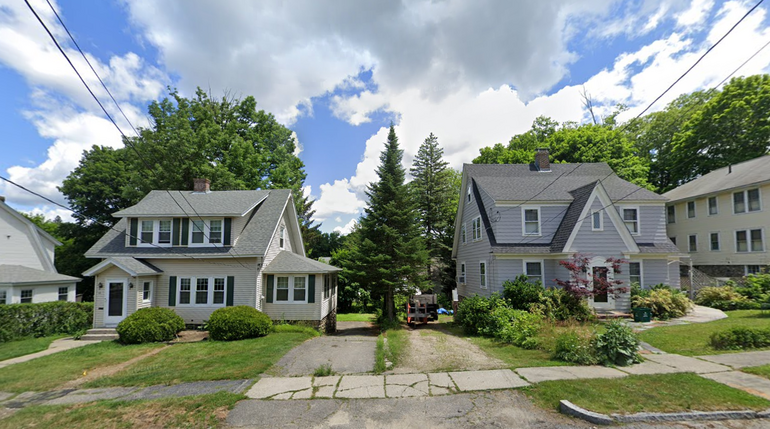 Two, two-story single-family homes with a tree and two driveways between them