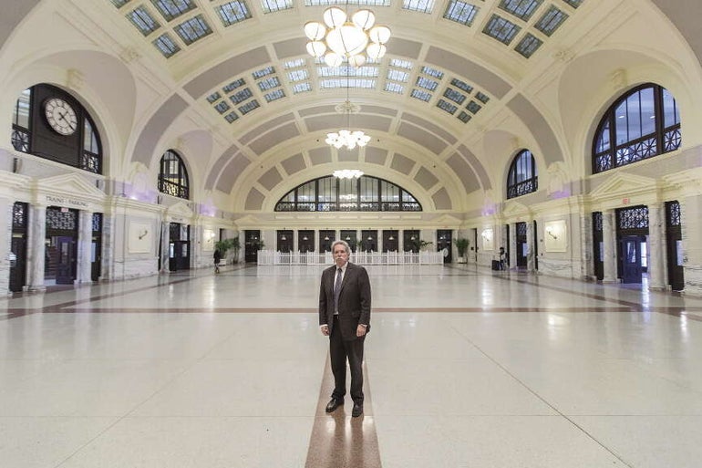 A man with grey hair wearing a suit stands inside a grand event space in Worcester's Union Station.