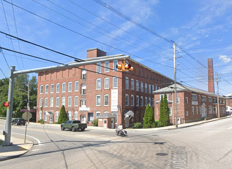 A large brick mill building with a street in front