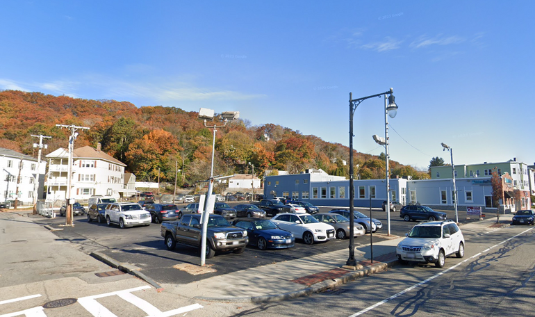 A parking lot sits in front of a wooded hill