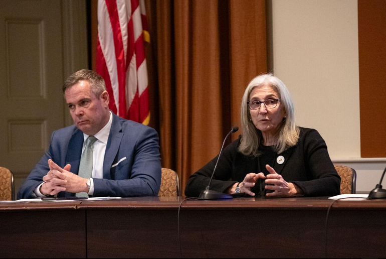 Man and women sit behind a table with microphone