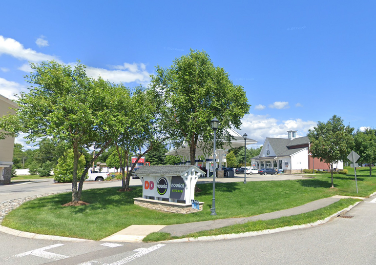 Outside of a gas station with signage and trees in front 