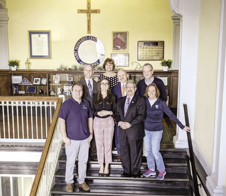A group of eight people stand on a staircase