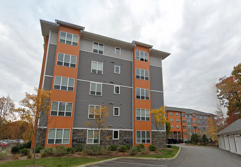A five-story apartment building with orange and grey paneling
