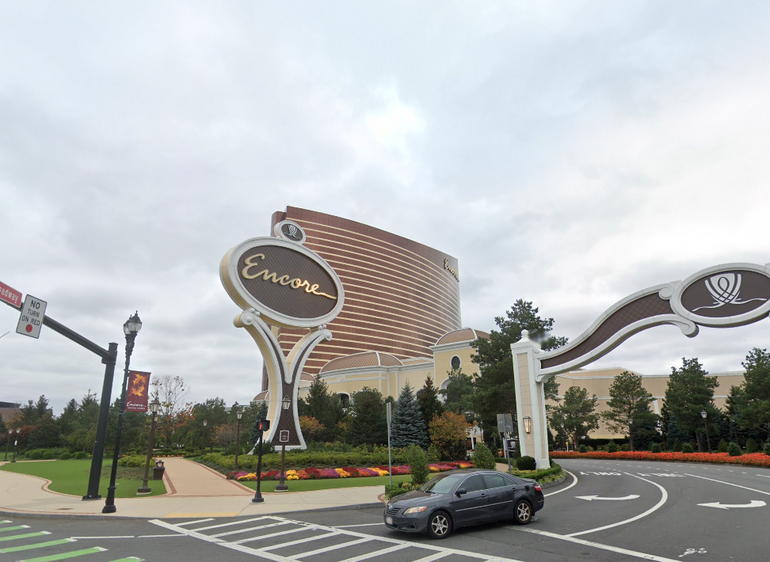 A casino driveway driveway with a large building and sign behind 