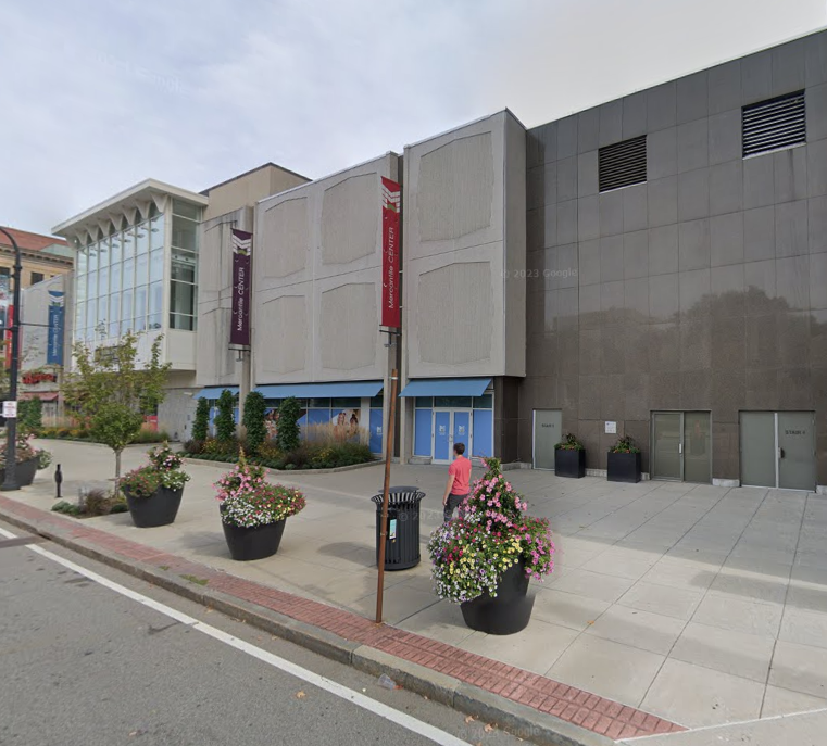 A two-story commerical building with a grey exterior in a downtown setting