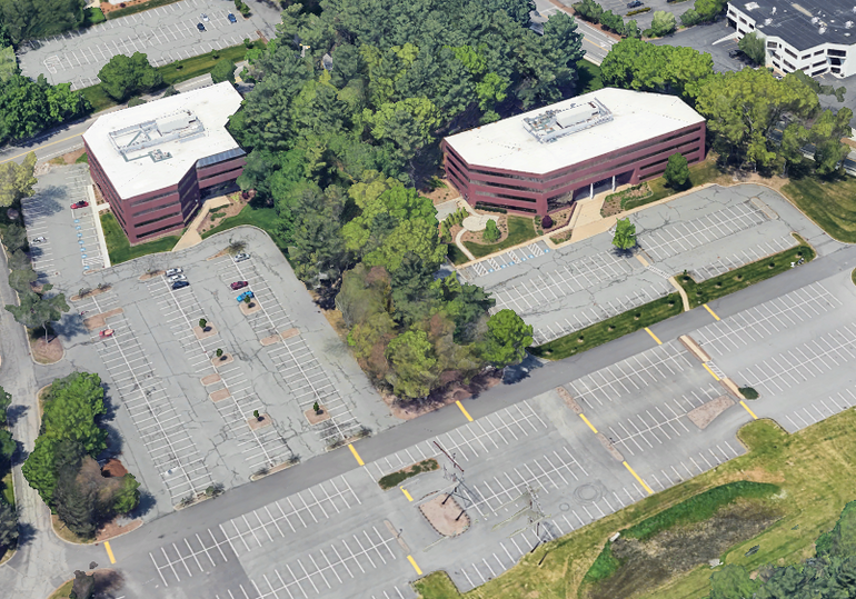 A 3D satellite rendering of two office building surrounded by empty parking lots