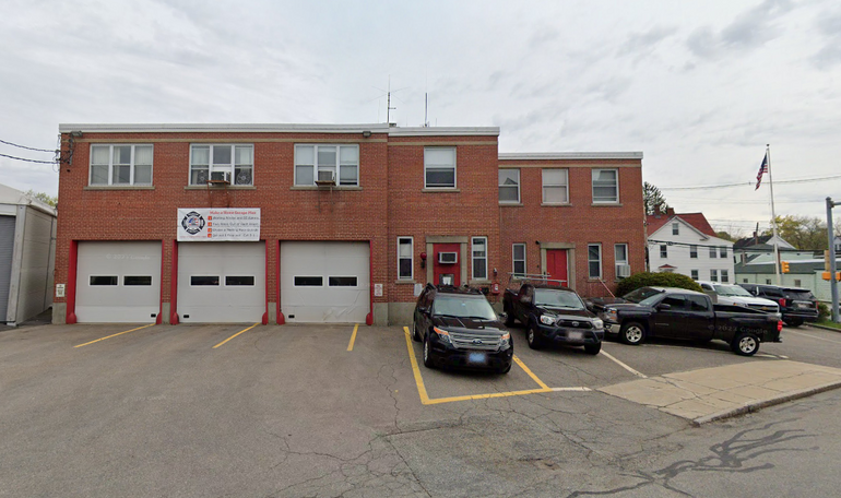 a two-story brick firehouse building with three garage doors