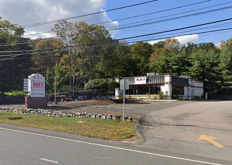 A small restaurant building sits behind a busy road