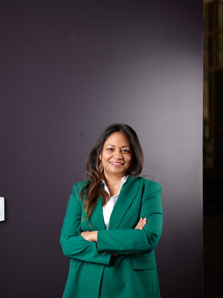 A woman in a green jacket smiles in a portrait photo