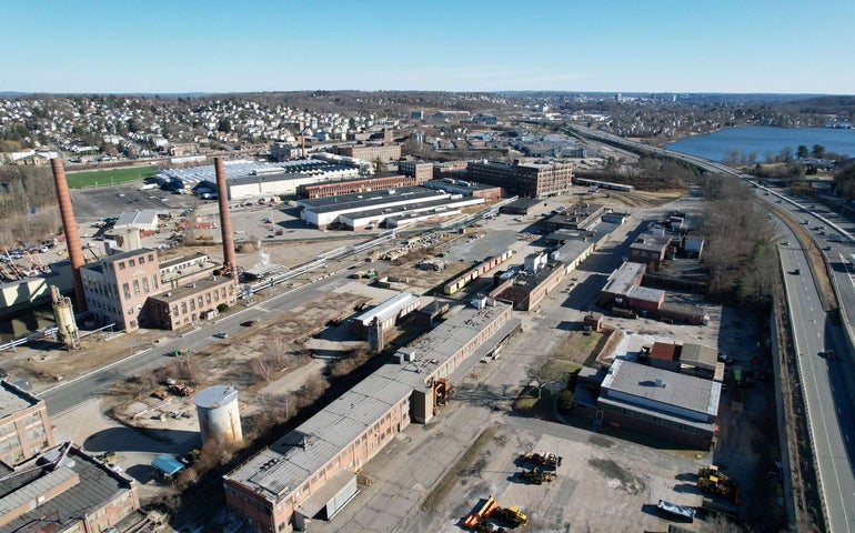 An aerial view of an industrial park with a highway running along the right hand side.