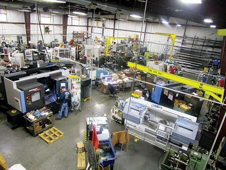 A cluttered warehouse with machines and people working at them