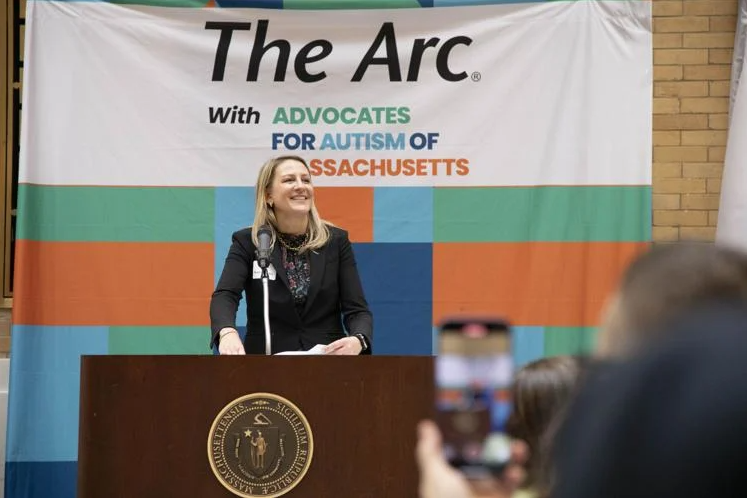 Woman stands at podium with microphone