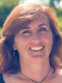 A woman with shoulder-length brown hair smiles for the camera.