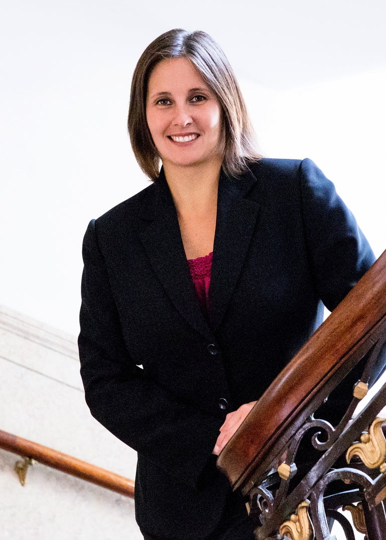 Woman in black dress suit leans on railing