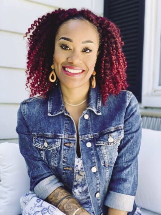 A woman with curly red hair wears a jeans jacket.