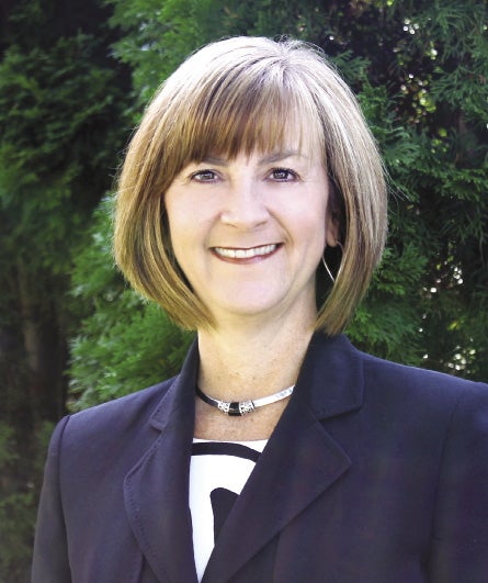 A woman with a light brown bangs and bob wears a dark blue blazer.