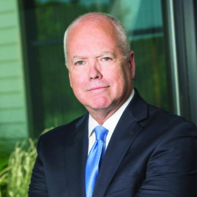 A man with white hair wears a suit.