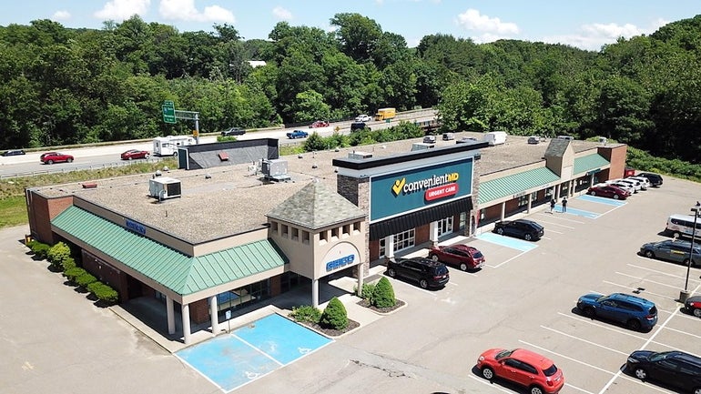 Aerial view of shopping plaza with highway behind it