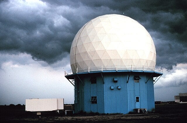A Doppler weather radar facility with storm clouds behind
