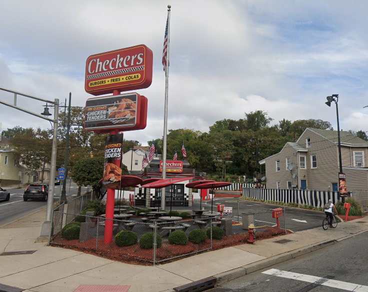 A Checkers fast food location with outdoor seating and a sign