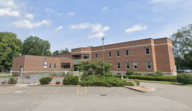 A two-story brick building sits behind an empty parking lot