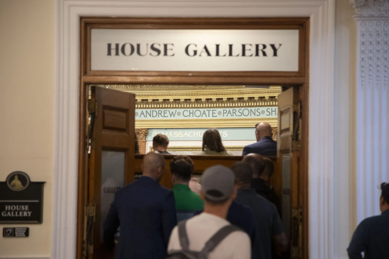 People seen from behind entering through a double door labeled "HOUSE GALLERY"