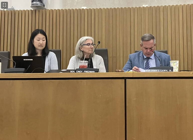 Three people sit at a podium