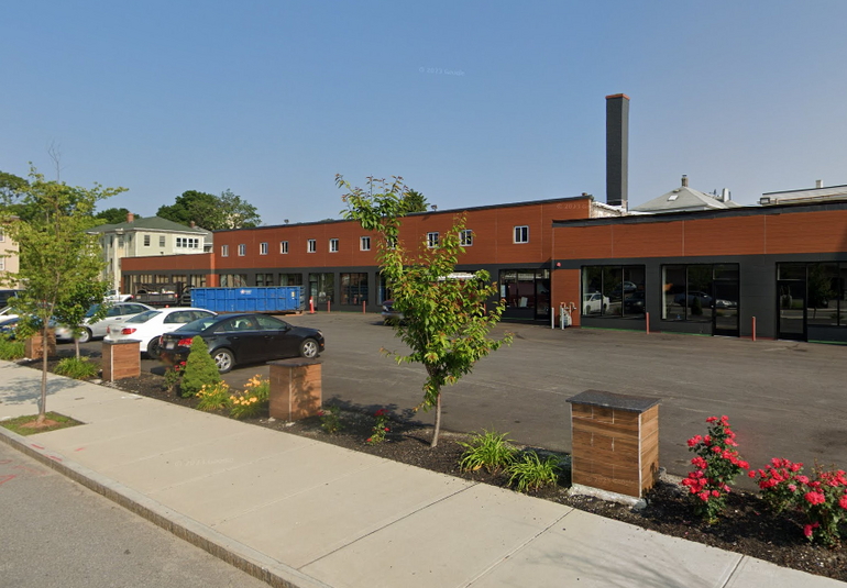 A two-story brick building sits behind a parking lot