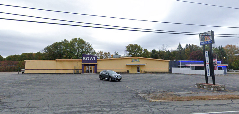 A one-story bowling center with large parking lot in front