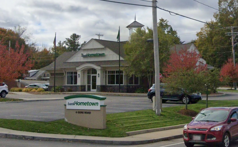 A bank branch location, with a sign out front and a parking lot in between