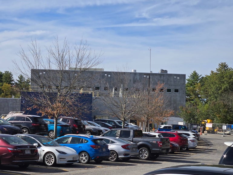  A building under construction sits behind parked cars