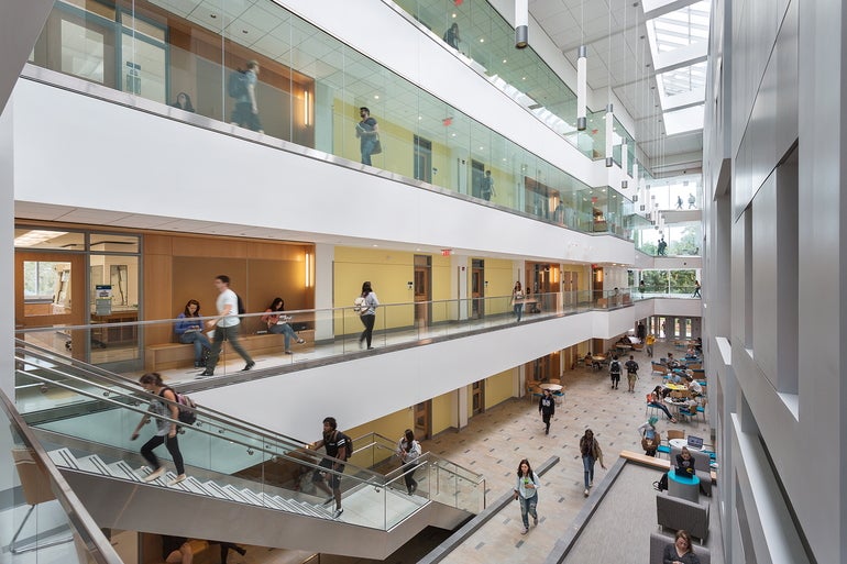 College students walk around an academic building with stairs.