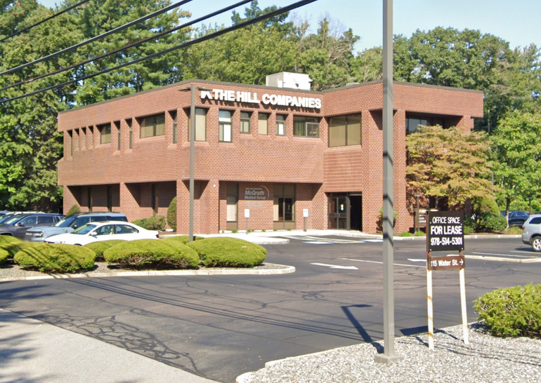 Three-story brick office building behind parking lot