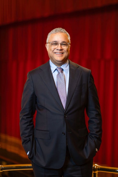 Man in suit stands in front of a red curtain