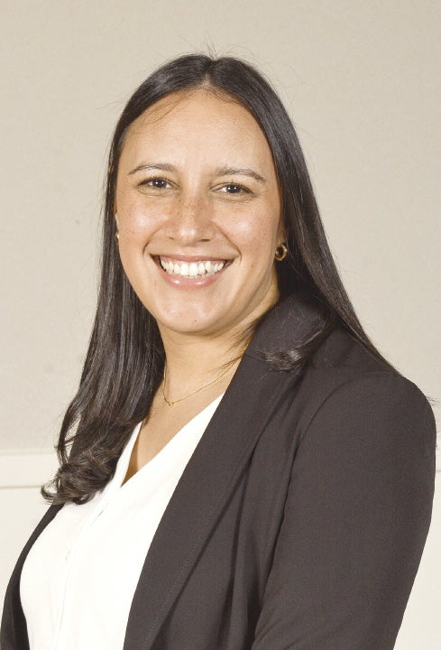 A woman with black hair is wearing a white shirt and black jacket.