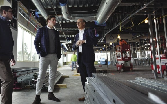 Three men talk in an interior construction site.