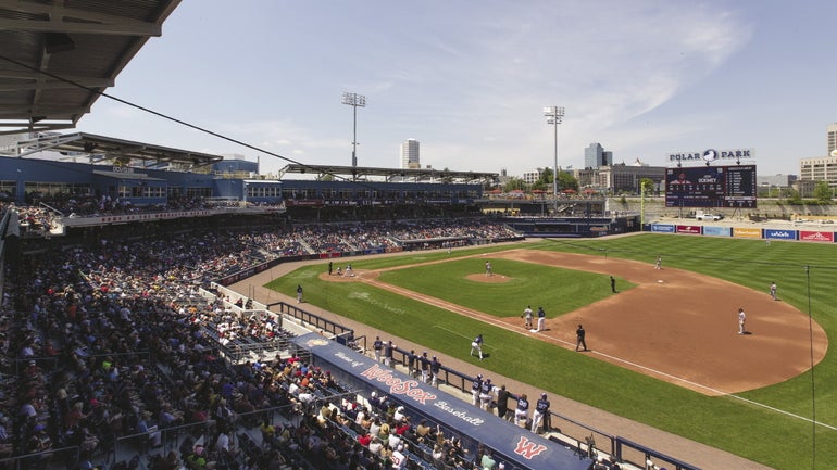 View of a baseball field on the right with fans in stadium seating on the left.