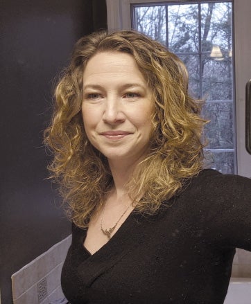 A woman with blonde wavy hair wears a black top.
