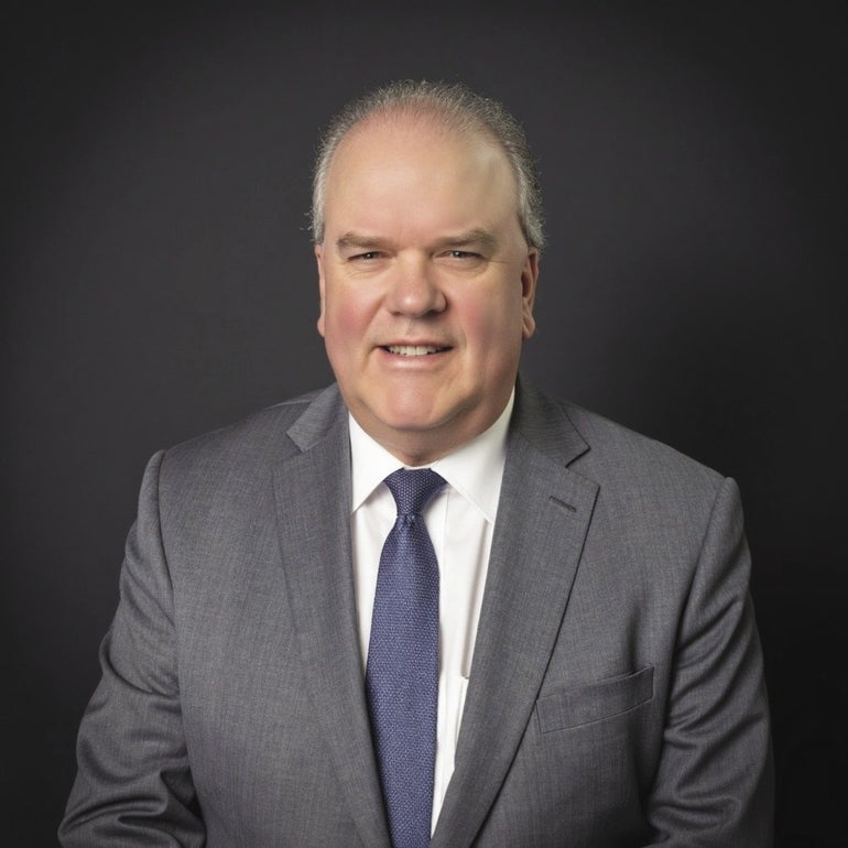 A man in a grey suit and blue tie