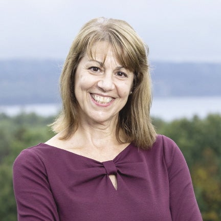 A woman with blond hair wears a purple shirt