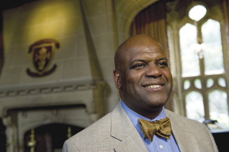 A man smiles in a suit and bowtie