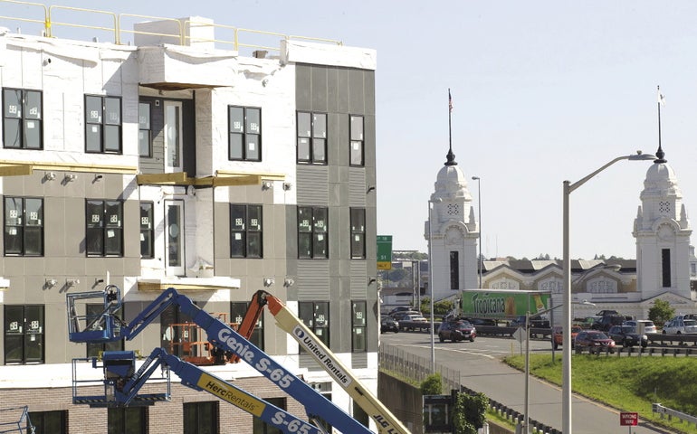 Lifts are arranced outside of an under-construction housing development with Worcester's Union Station in the background