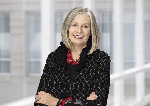 A woman with a grey bob wears a black patterned sweater.