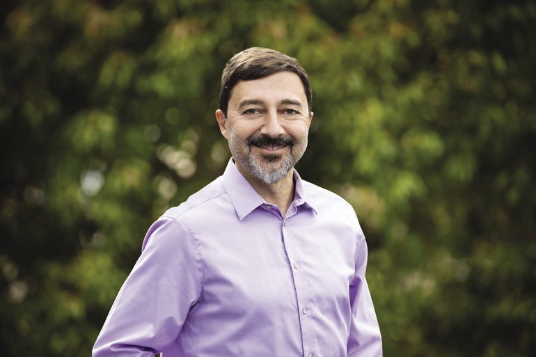 A man in a light purple shirt and a beard