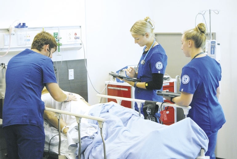 Three Assumption University nursing students practice on a dummy patient.